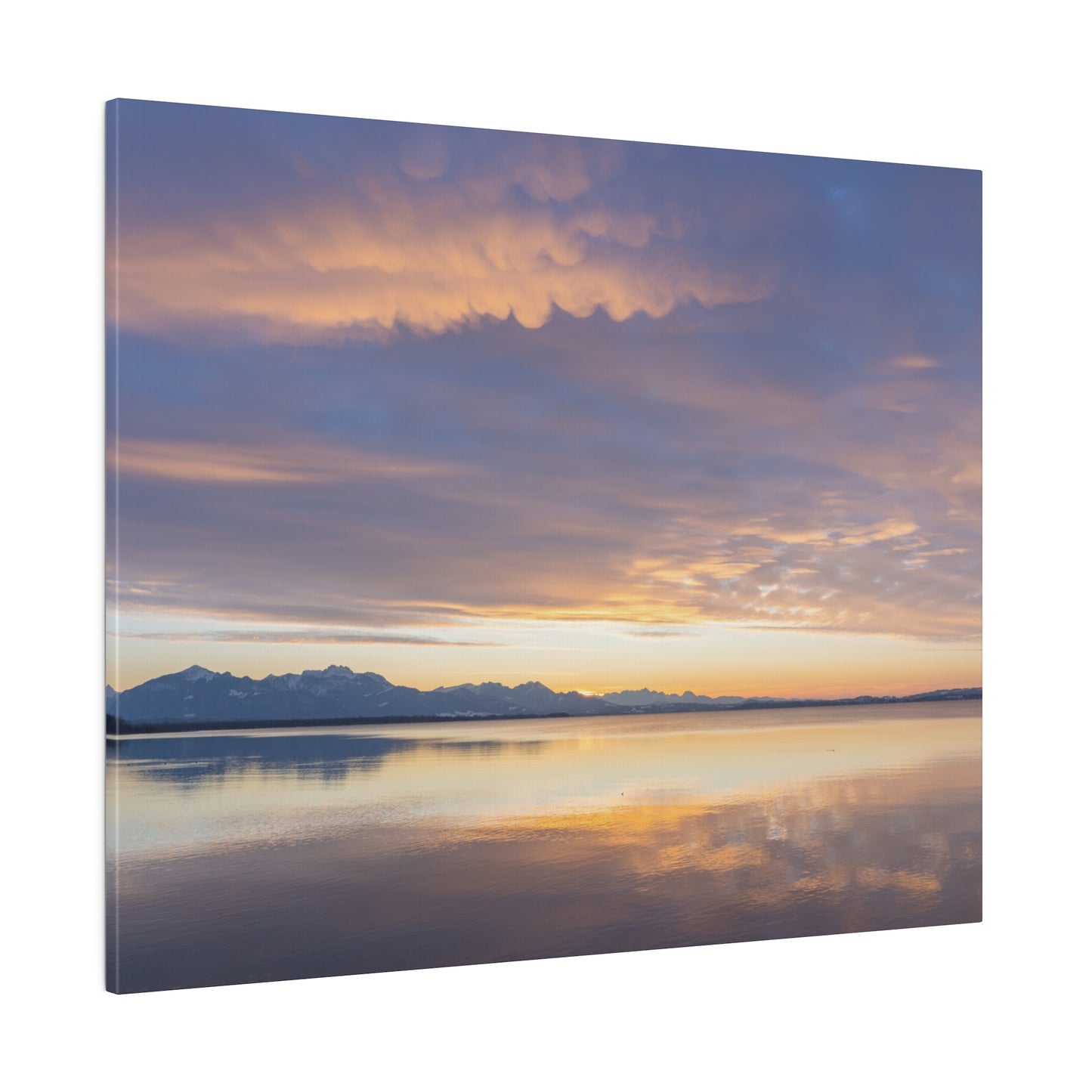 Evening serenity over a lake, with the setting sun illuminating the clouds in soft colors. The calm water reflects the peaceful sunset scene, enhancing the tranquility.