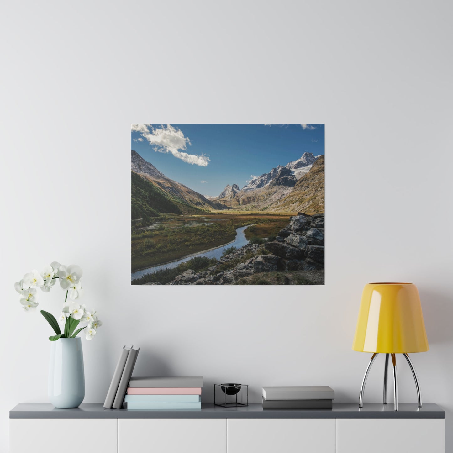 A stunning mountain valley view with a winding river, surrounded by towering peaks and clear blue skies. The scene is serene and picturesque.