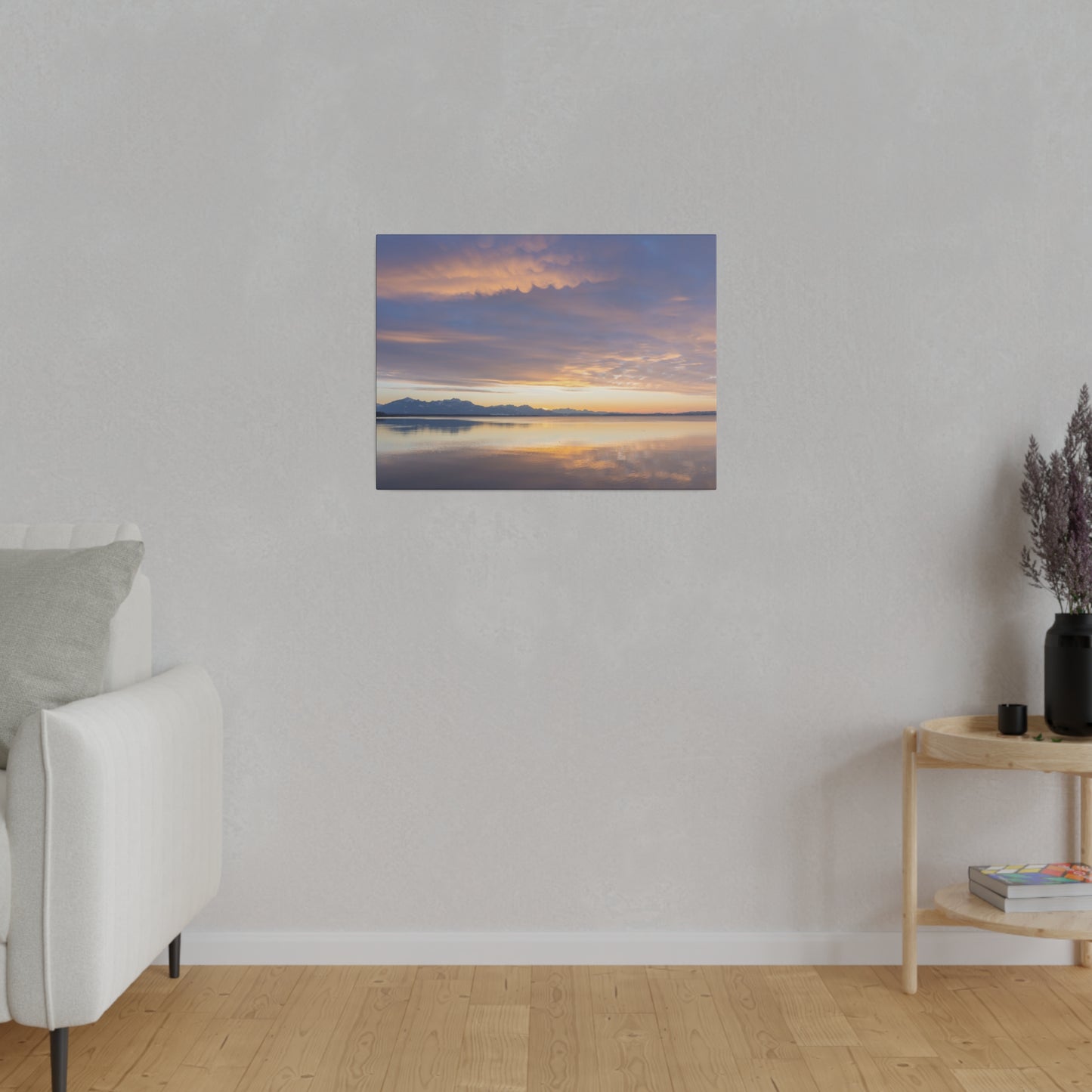 Sunset hues over a calm lake, with soft clouds glowing in shades of orange and purple. The peaceful water reflects the serene colors of the sky.