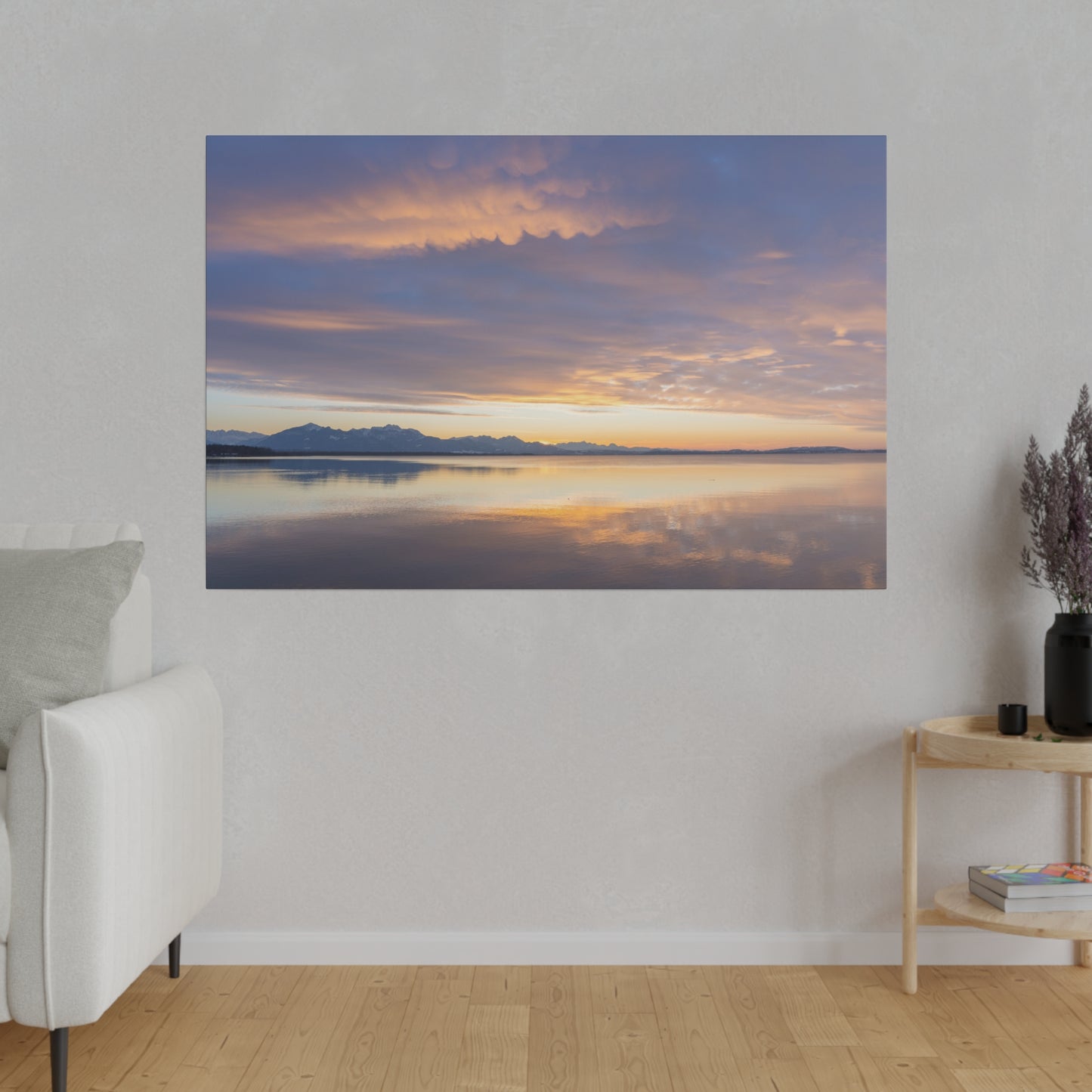 A stunning sunset sky over a calm lake, with soft clouds illuminated in vibrant hues of orange and purple. The peaceful scene is reflected on the still water.