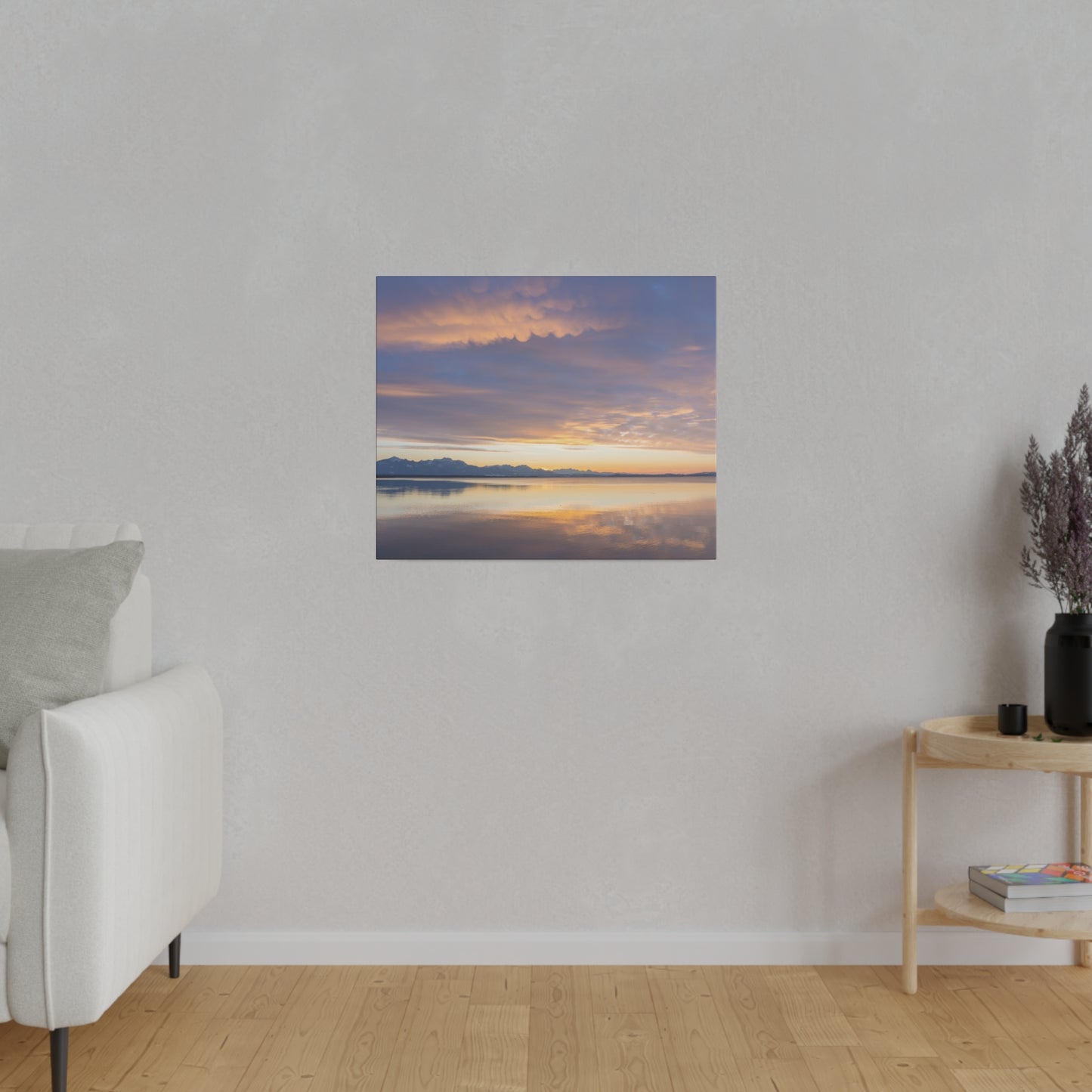 A tranquil evening sky with gentle clouds illuminated by the setting sun. The calm lake below mirrors the stunning colors of the sunset, creating a peaceful atmosphere.