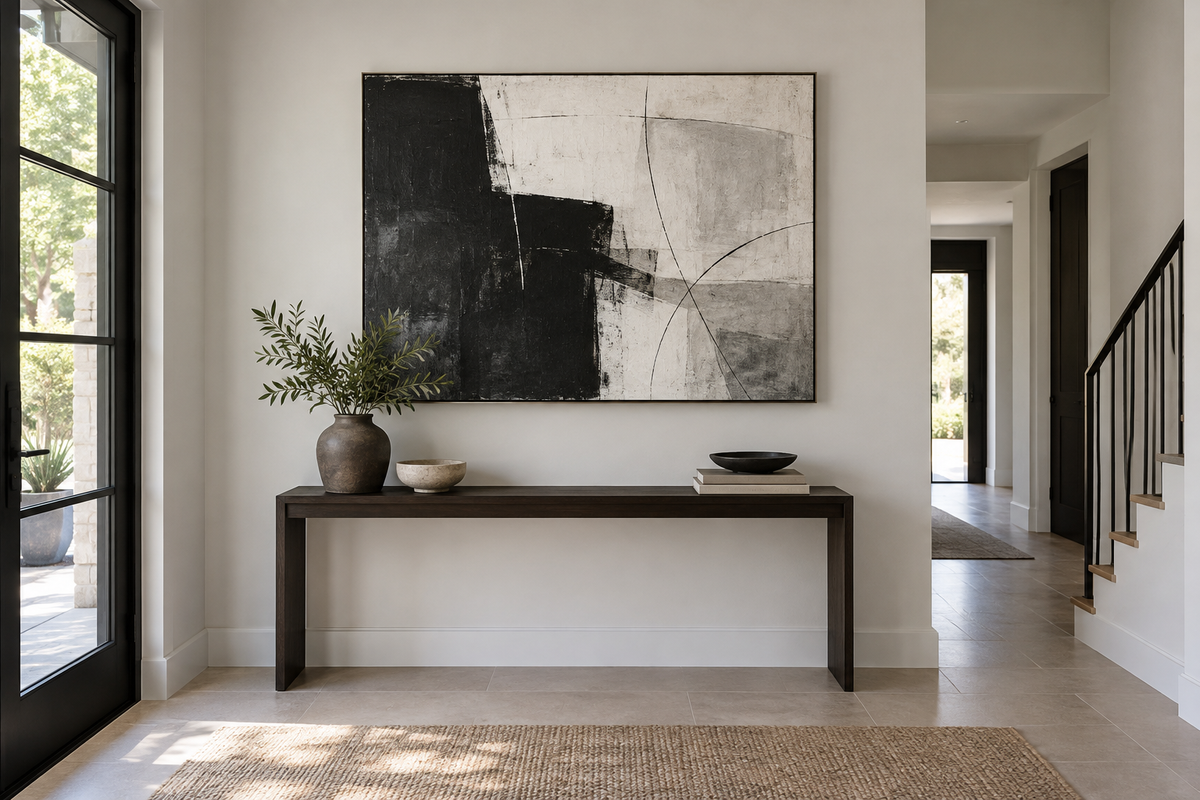 Black and white abstract canvas print above a slim dark wood console in a softly lit modern hallway.