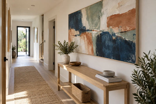 Large abstract canvas in indigo, sage, terracotta and cream above a console in a bright hallway.