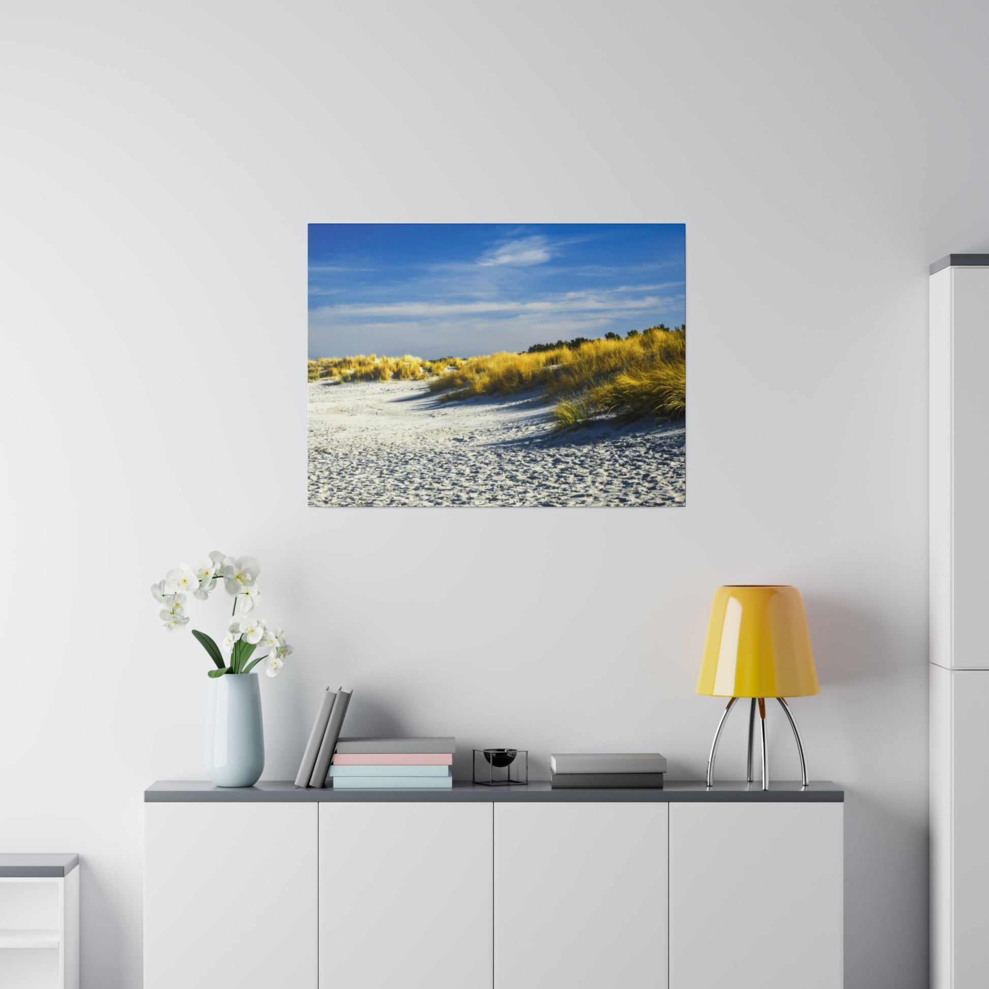 Golden grasses on a sandy beach with a bright blue sky, offering a peaceful and serene landscape.