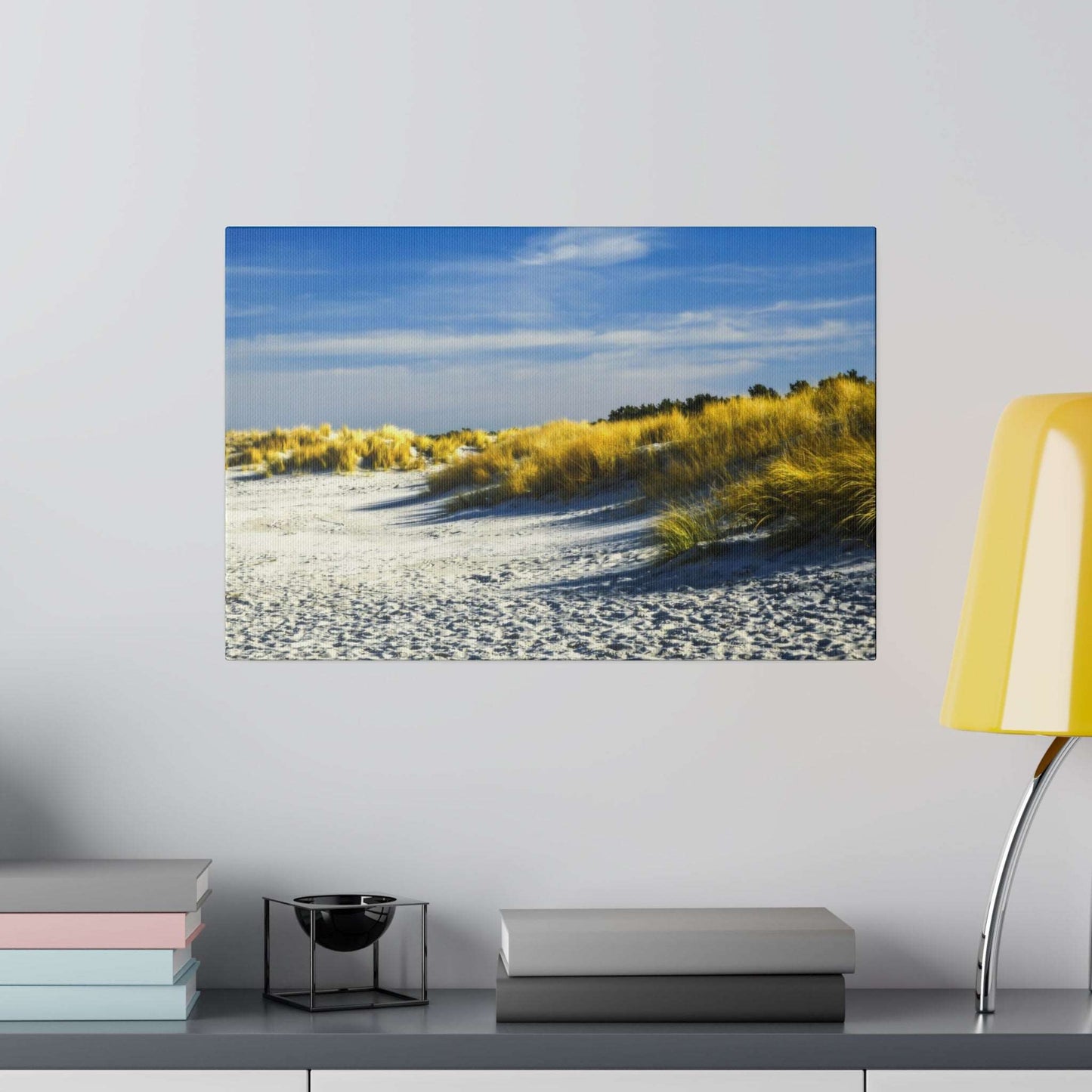 Golden dune grasses on a beach with bright blue skies, casting long shadows on the white sand.