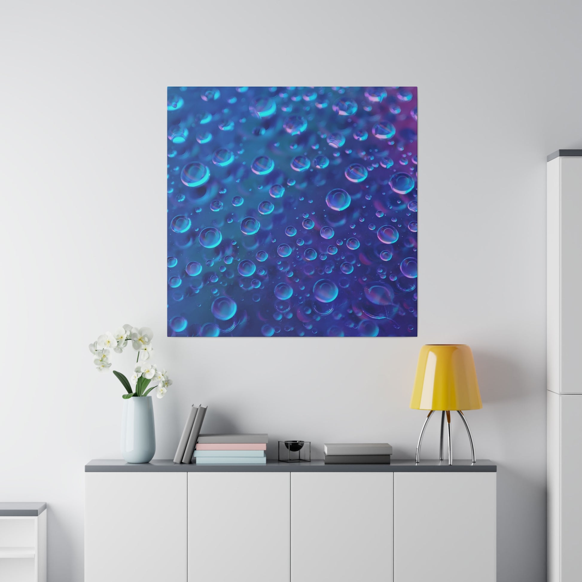 Blue abstract wall art with numerous bubbles in blue and purple tones above a white console, yellow lamp, and vase.