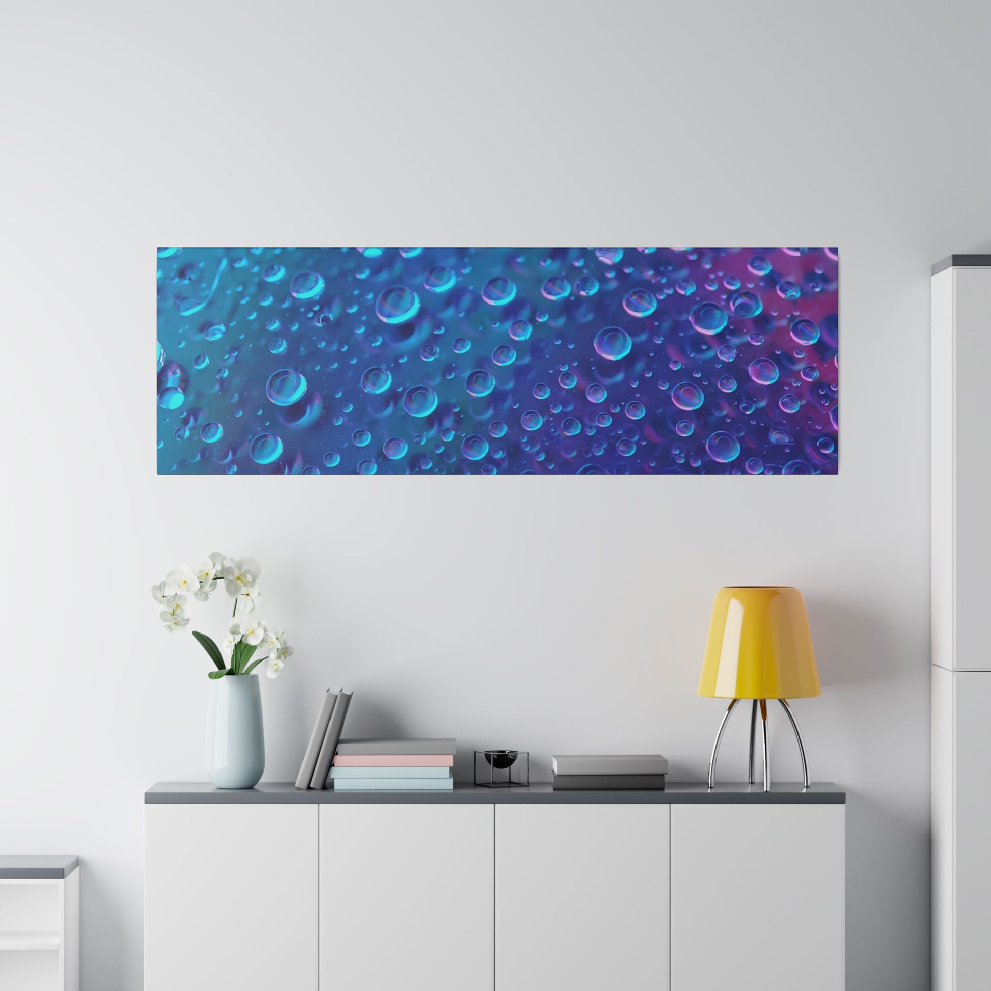 Rectangular wall art with a blue-to-purple bubble pattern mounted above a white cabinet in a bright living space.