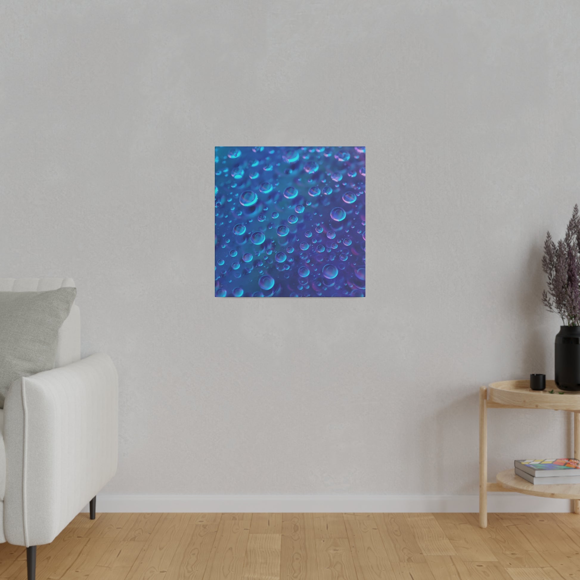 Square blue abstract print with numerous bubbles on a blue gradient, hung on a light gray wall in a modern living room.