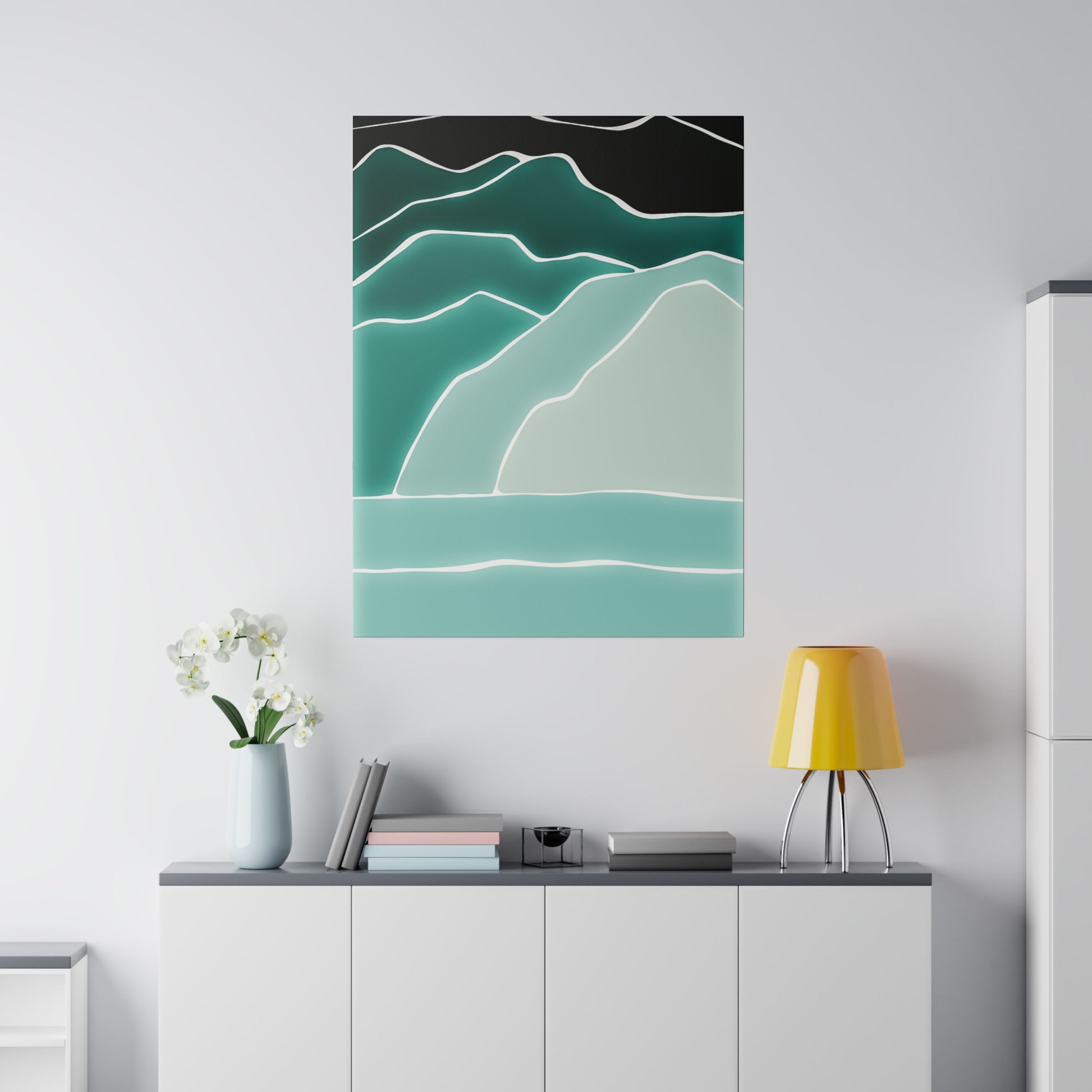 Abstract teal mountain landscape poster with layered white outlines mounted on a white wall above a white cabinet.