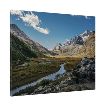A mountain valley with a winding river, green meadows, and snow-capped peaks under a blue sky.