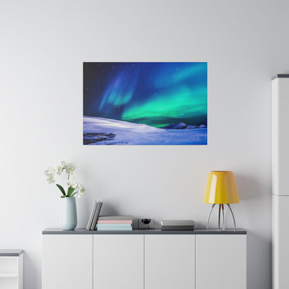 White cabinet topped with books, vase, and yellow lamp below a framed aurora borealis print on a light gray wall.