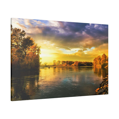 A river scene at sunset with golden light, trees along both banks, and a rocky shore on the right.