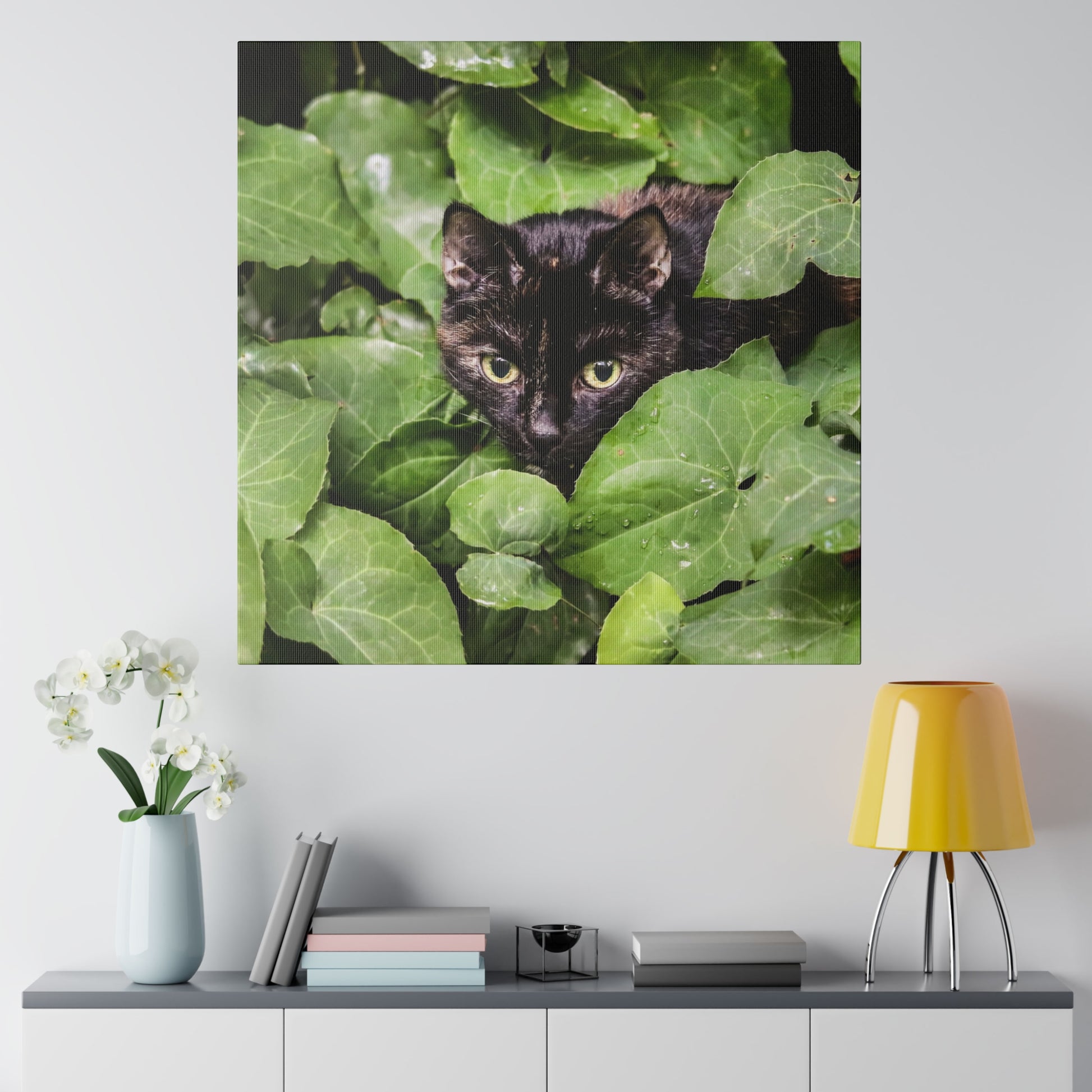 Close-up of a black cat's face peering through dense green leaves.