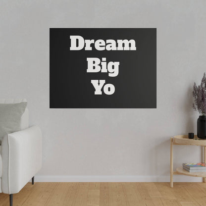 Black rectangular wall art with white stacked text "Dream Big Yo" on a light gray living room wall.