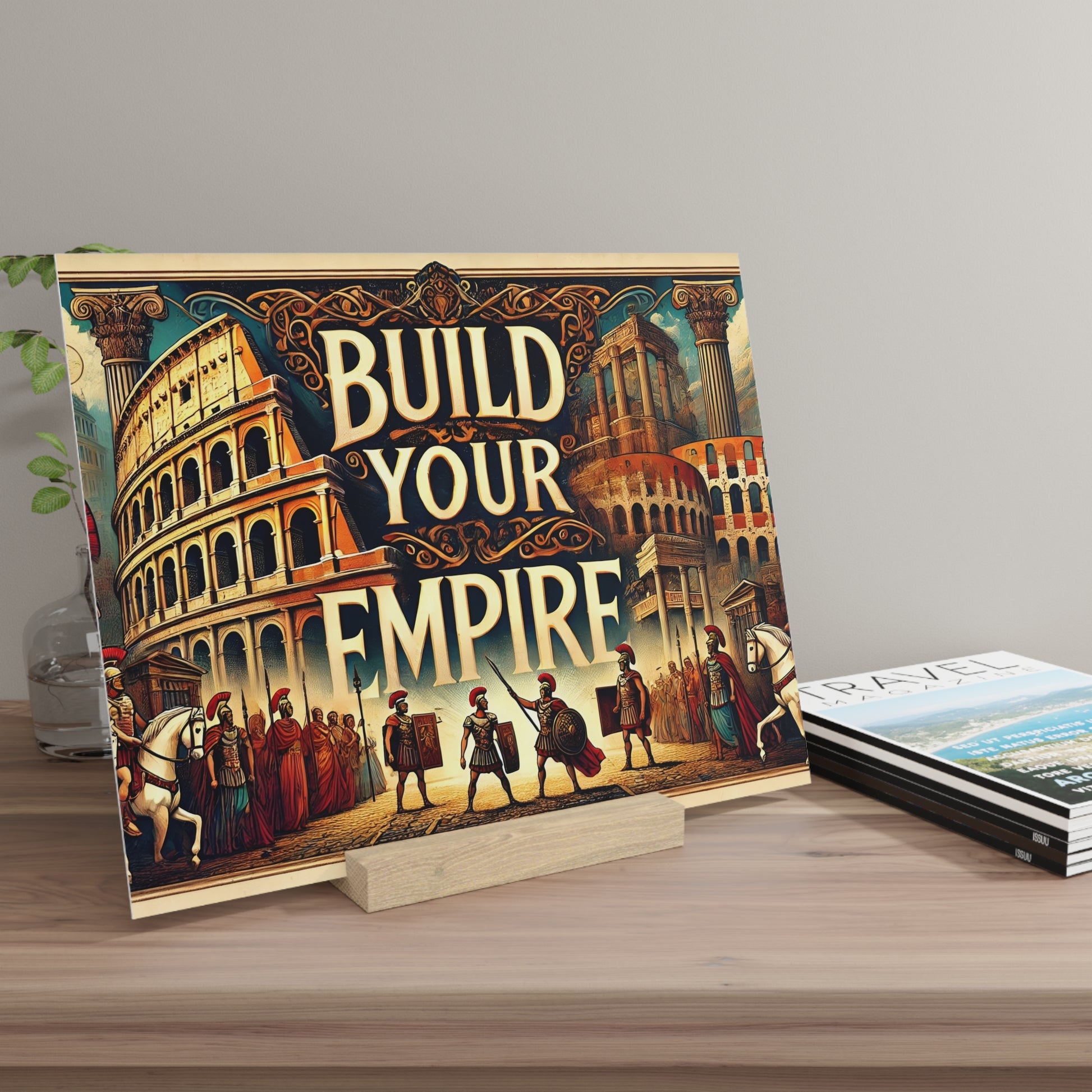 Colorful poster reading 'BUILD YOUR EMPIRE' with ancient Rome scenes and columns, propped on a small wooden stand on a desk.