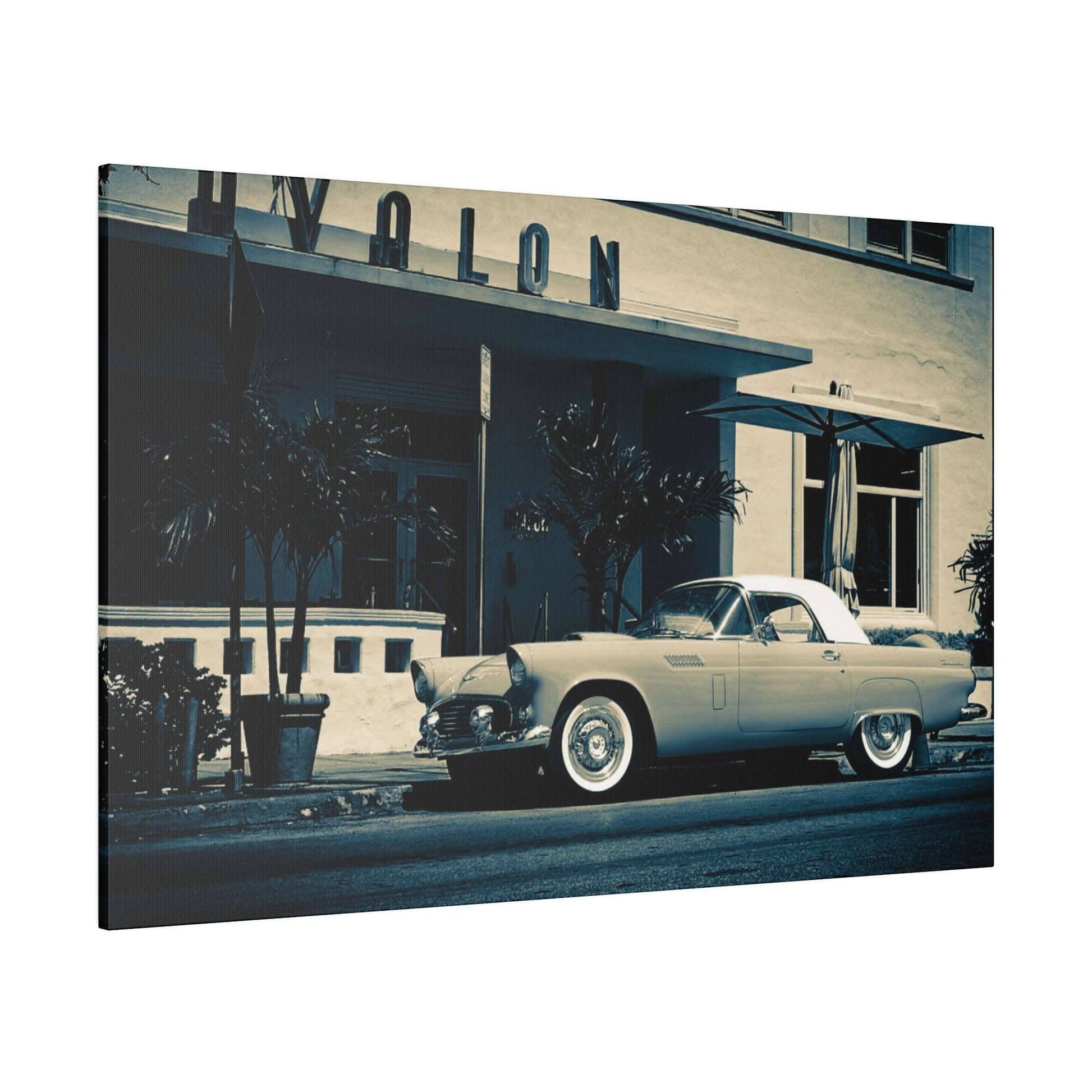 Cream-colored vintage convertible parked on a street in front of a mid-century hotel with palm trees.