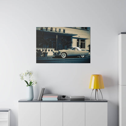 Light blue vintage convertible car parked in front of a beige building with palm trees.
