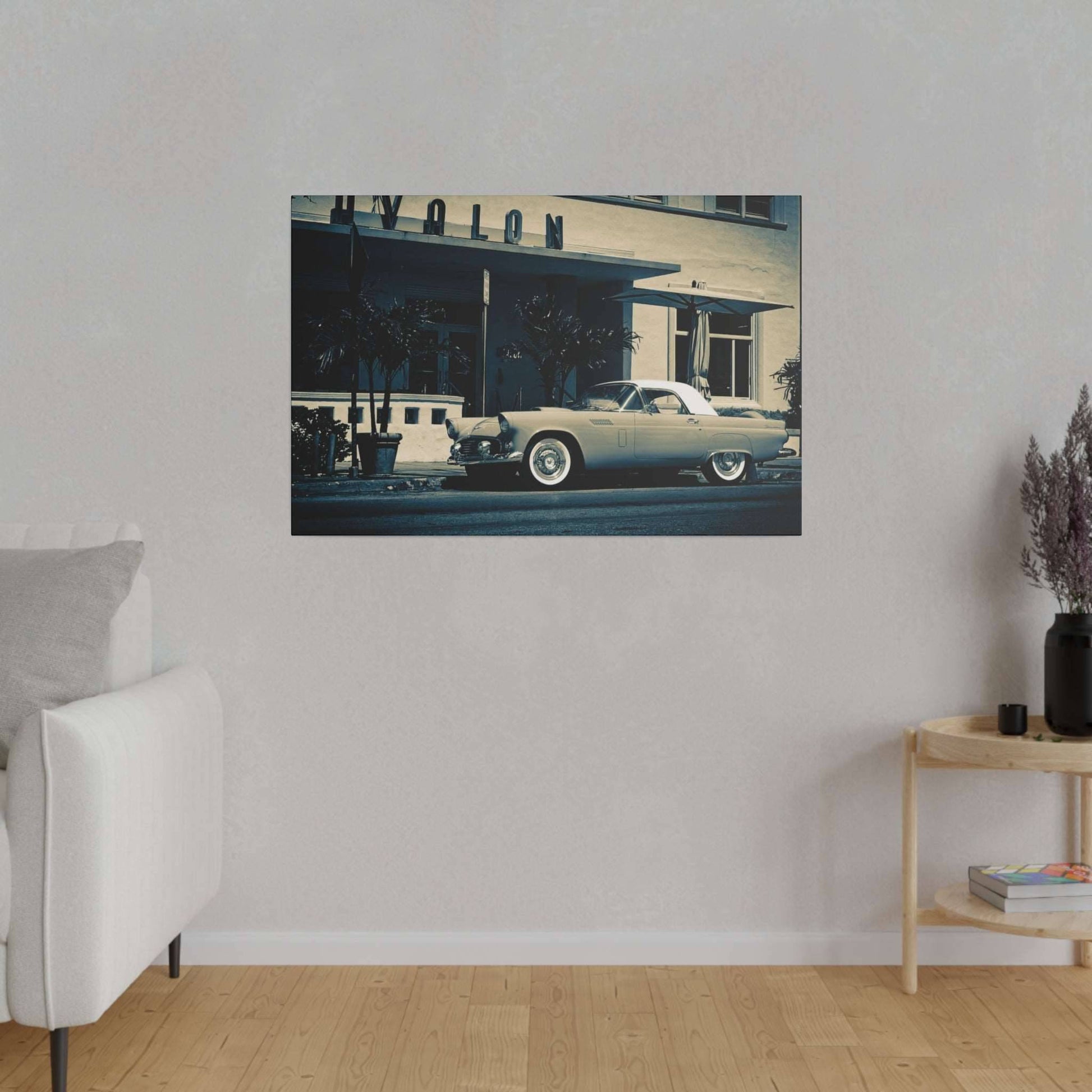 A beige living room wall with a framed vintage silver car artwork hung above a white sofa.