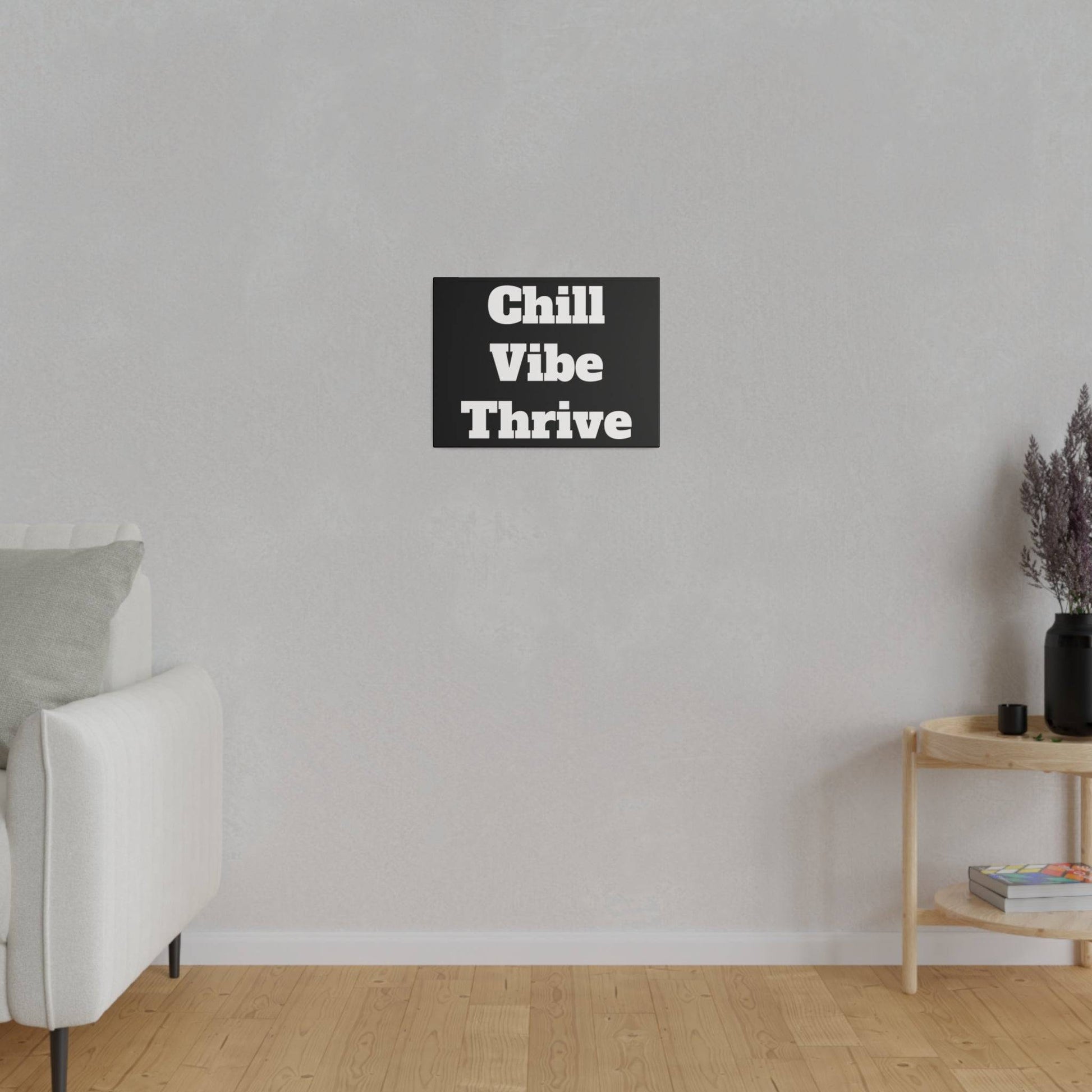 Light gray living room with a white sofa on the left, a wooden side table on the right, and a black wall art panel reading “Chill Vibe