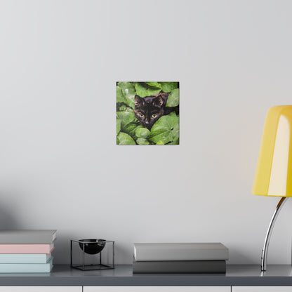 Small square wall art showing a black cat's face peeking through green ivy leaves.