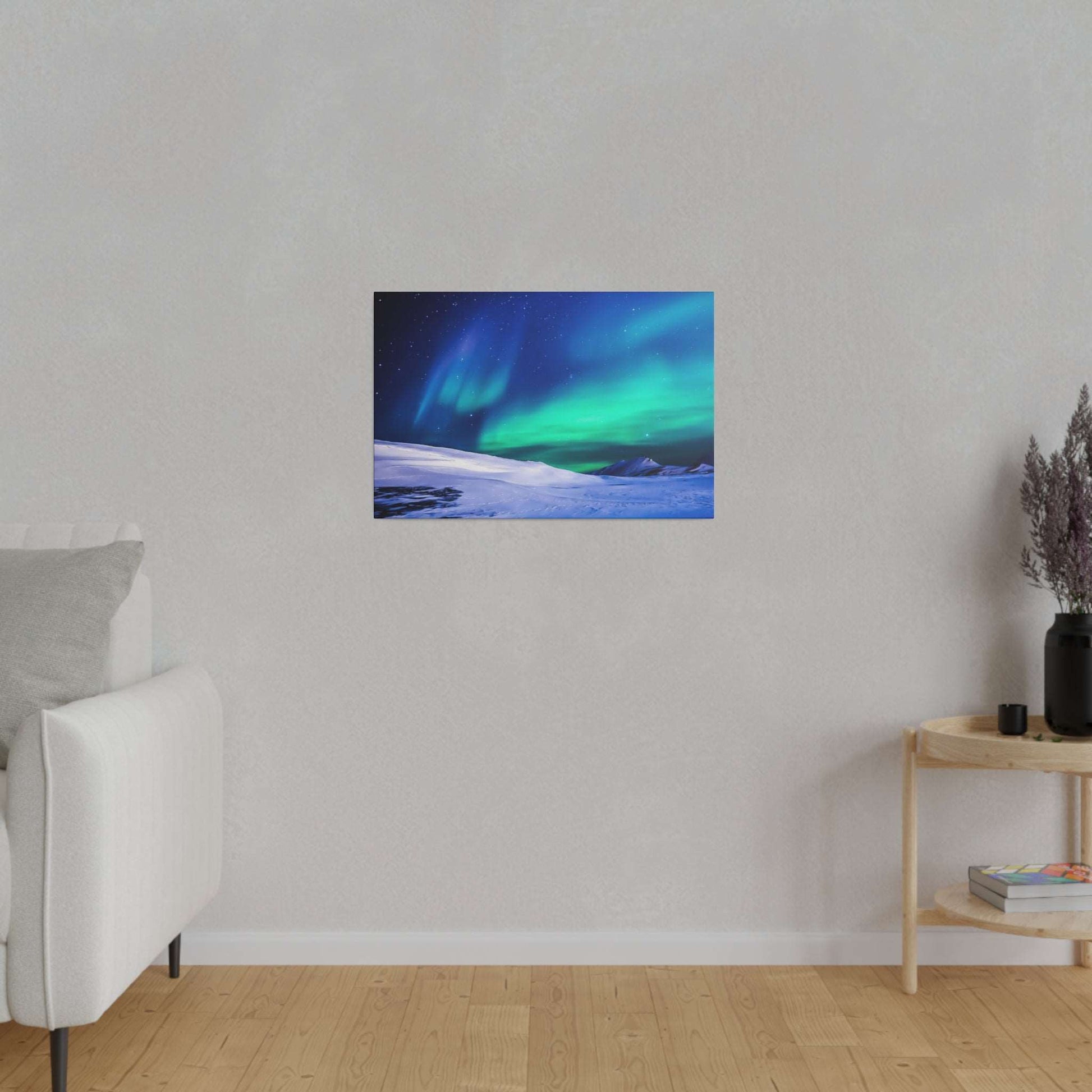 Canvas art print of green and blue Northern Lights over a snow-covered landscape, mounted on a light gray wall.