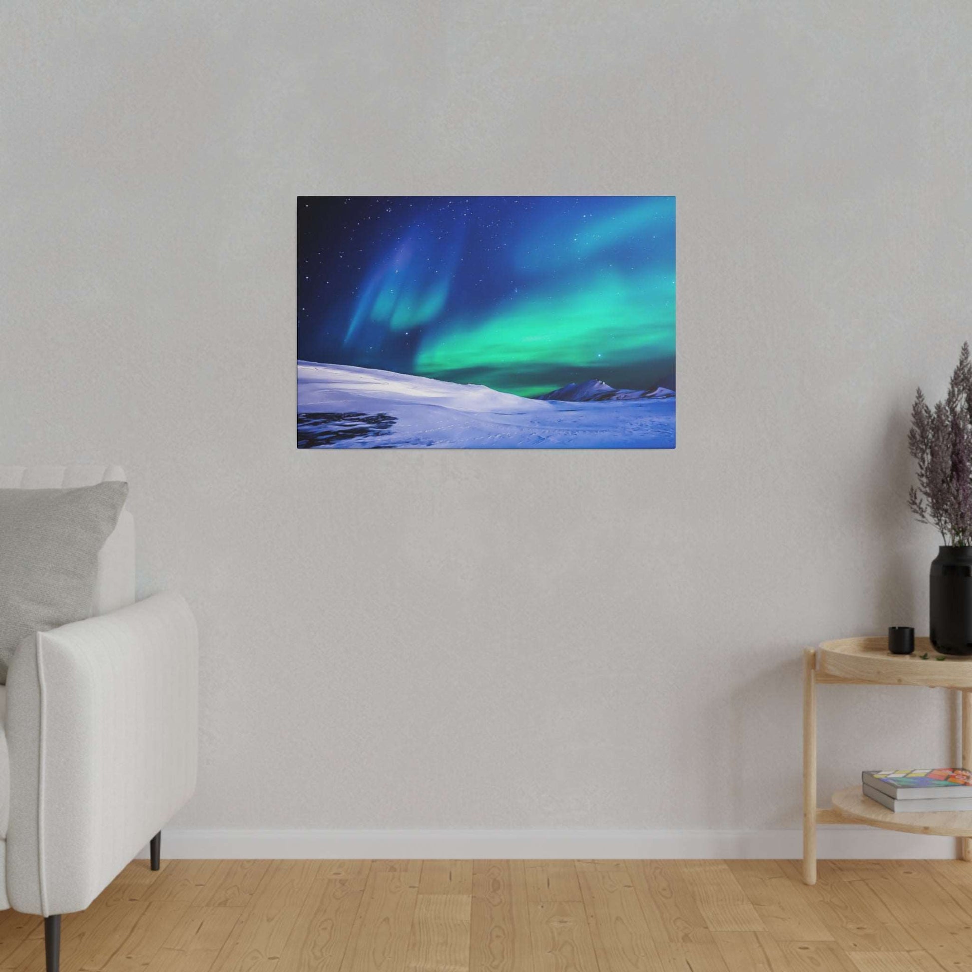 Canvas print showing green and blue aurora borealis across a snow-covered landscape, hung on a light gray wall.
