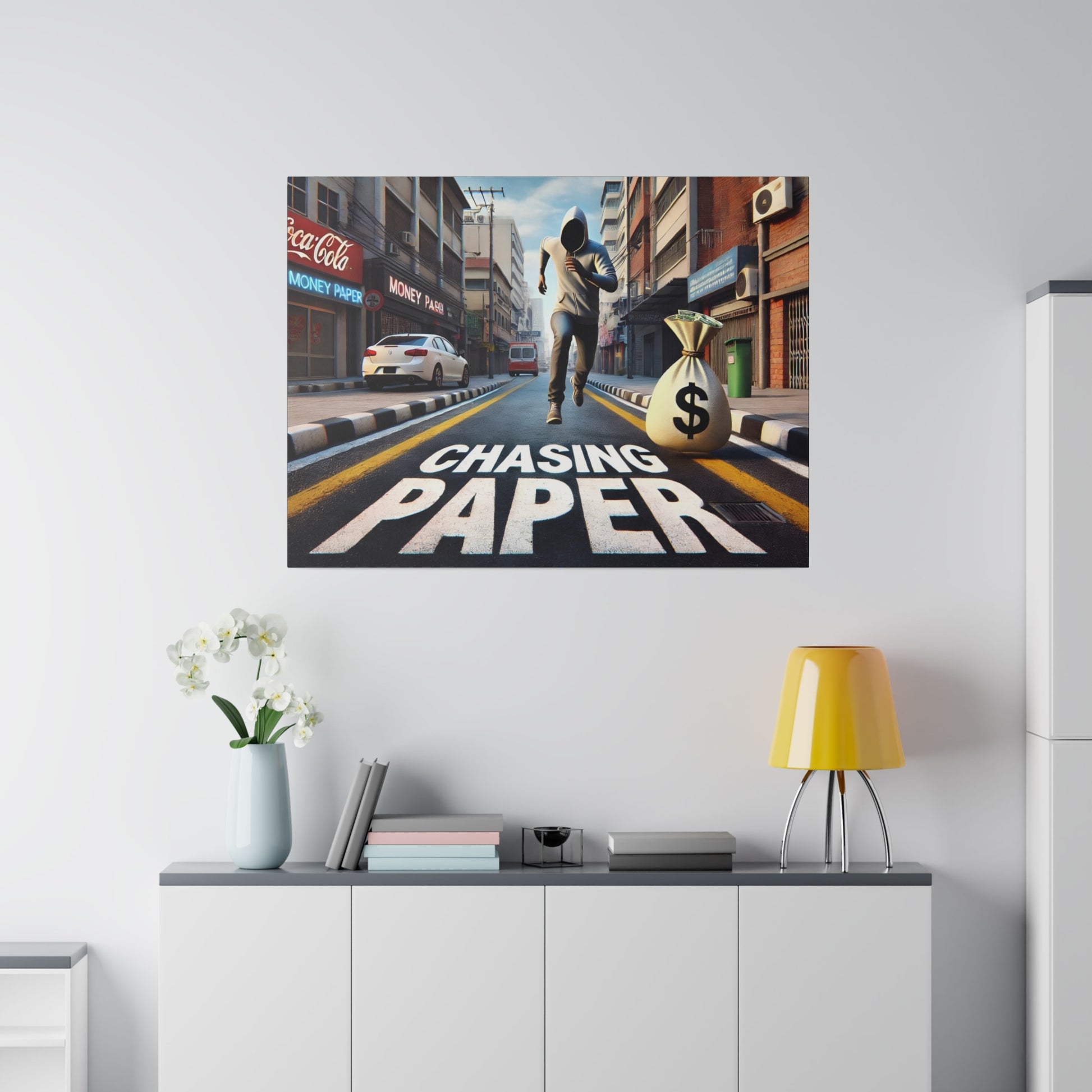 Decorative wall art showing a man running down a city street with a large money bag and the words “CHASING PAPER.”