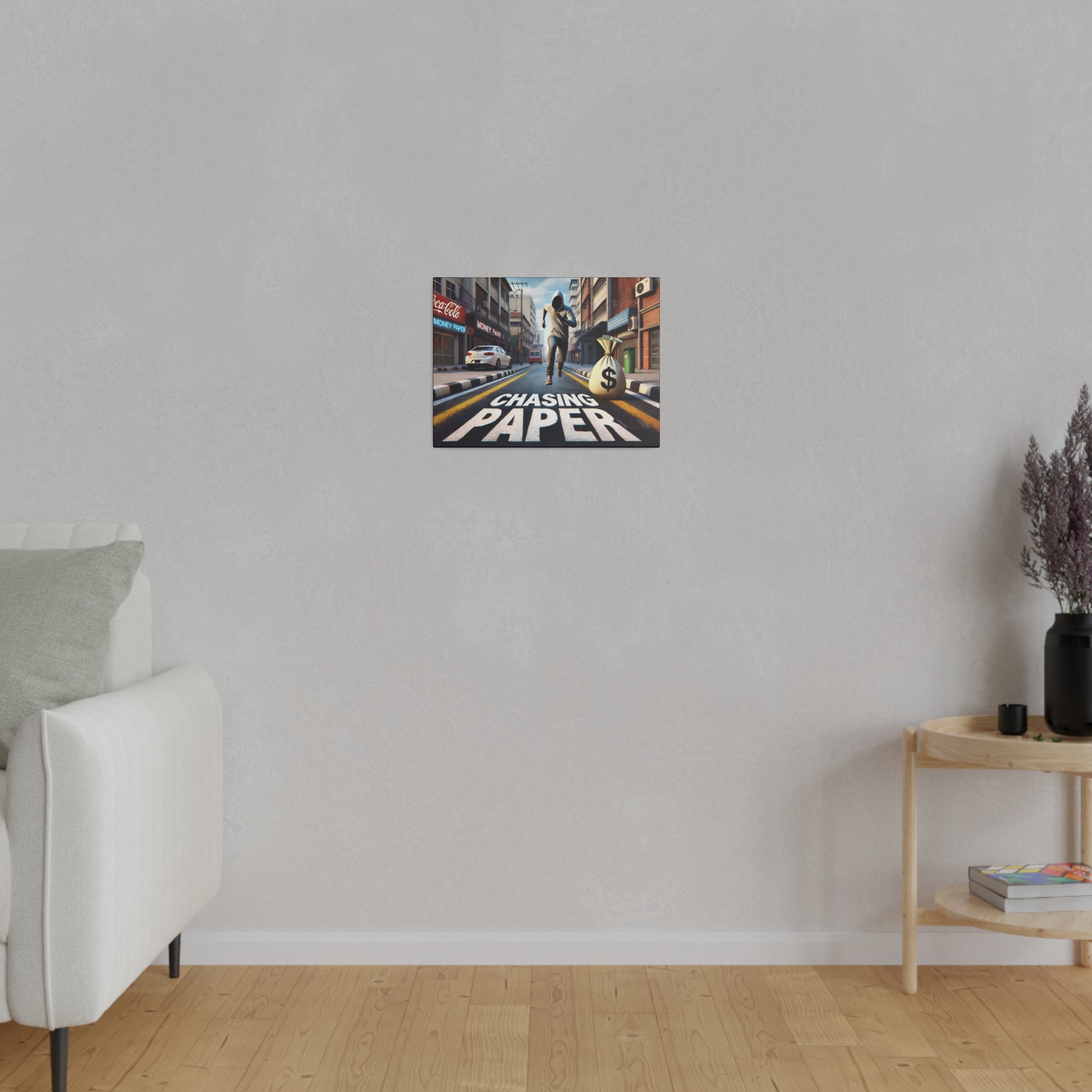Small rectangular poster on a light gray wall depicting a city street scene with a runner and the words "CHASING PAPER".