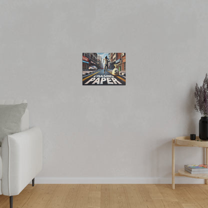 Small rectangular poster on a light gray wall depicting a city street scene with a runner and the words "CHASING PAPER".