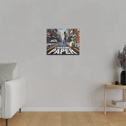 Small framed poster on a light gray wall shows a city street with a money bag and the text “Chasing Paper.”