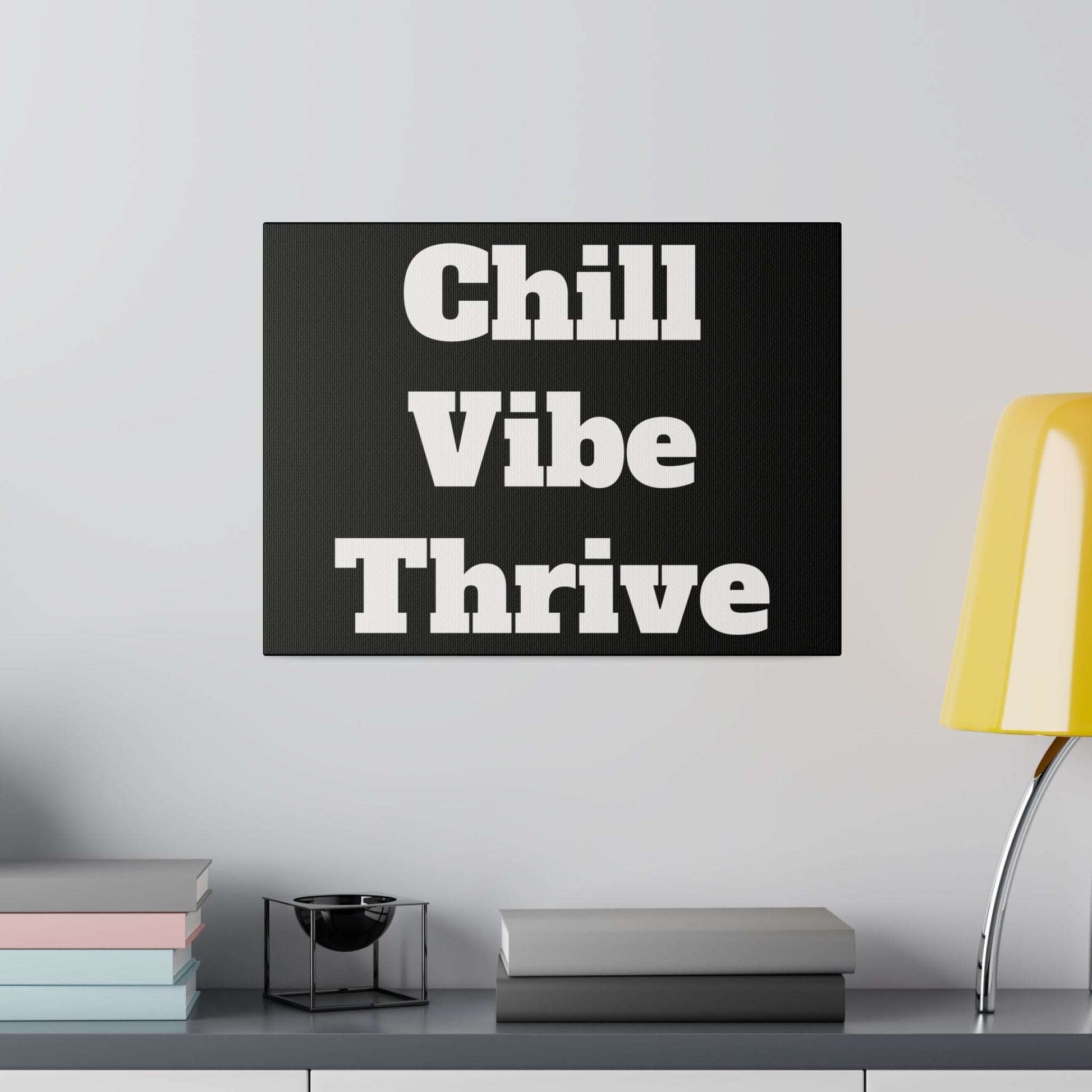 Black square sign with bold white text reading "Chill Vibe Thrive" on a light gray wall.