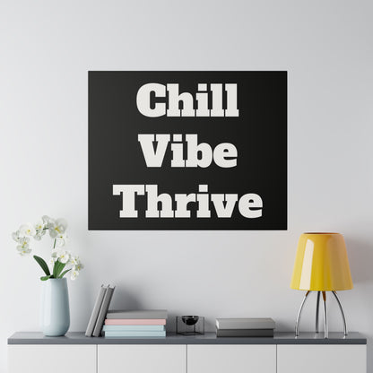 Black square poster with bold white text reading “Chill Vibe Thrive” on a light wall above a cabinet.
