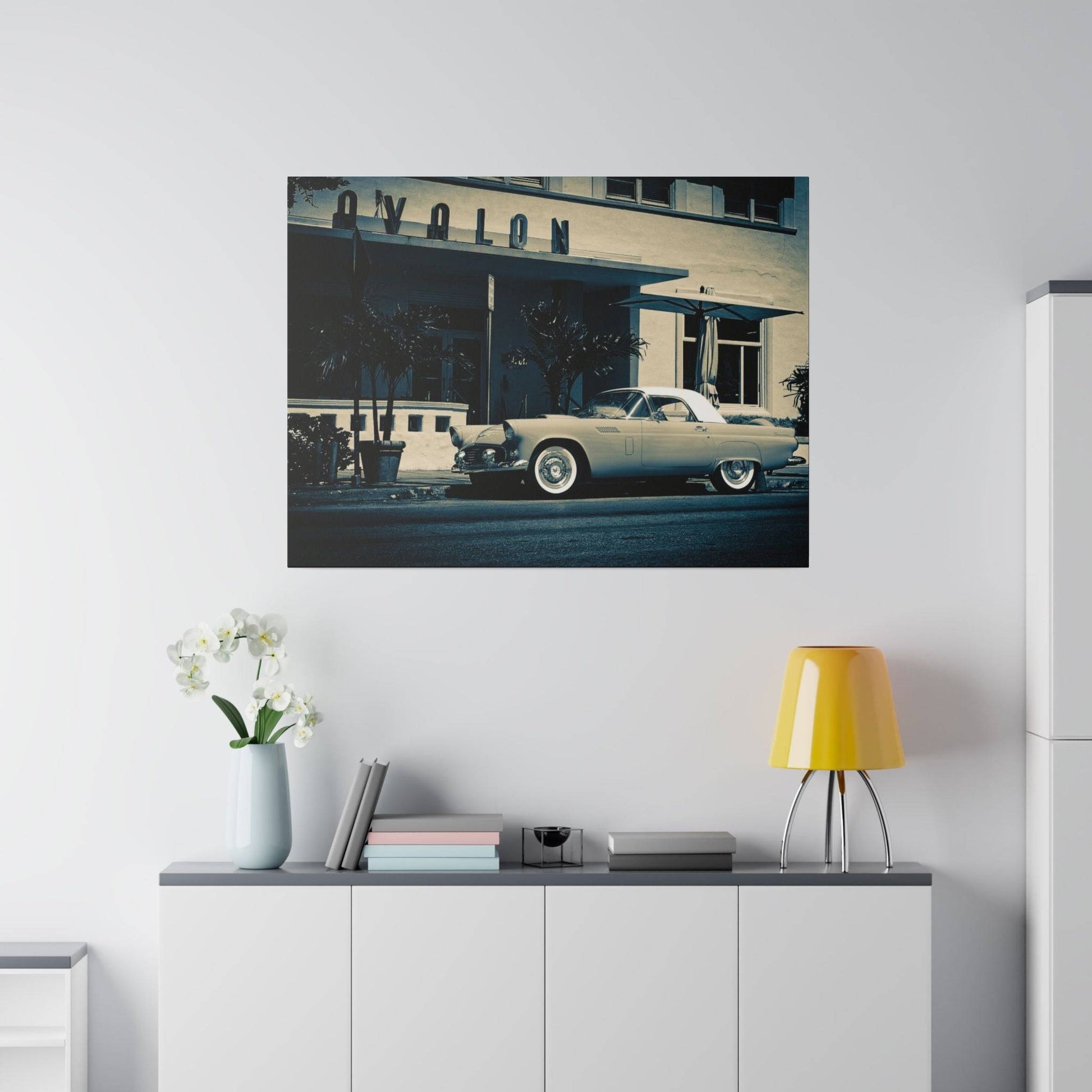 A vintage light-blue car parked on the street in front of a beige mid-century building.