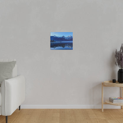 Small square wall art showing a blue mountain lake and its reflection on calm waters, mounted on a gray wall.
