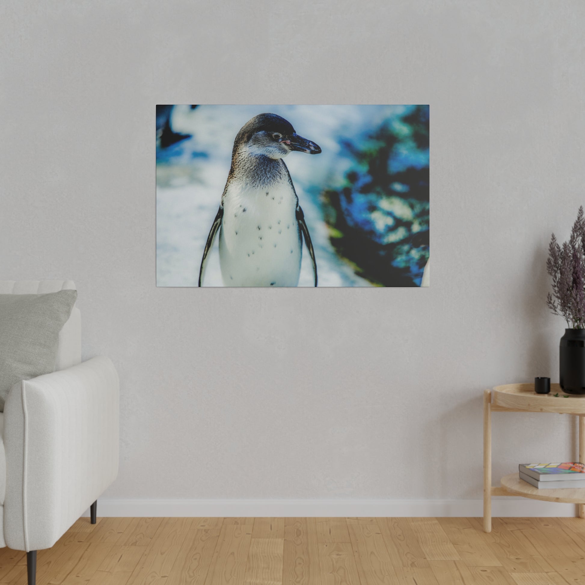 A close-up of a penguin standing in the snow, with a blurred background of blue and white. The image showcases the penguin in its natural habitat.