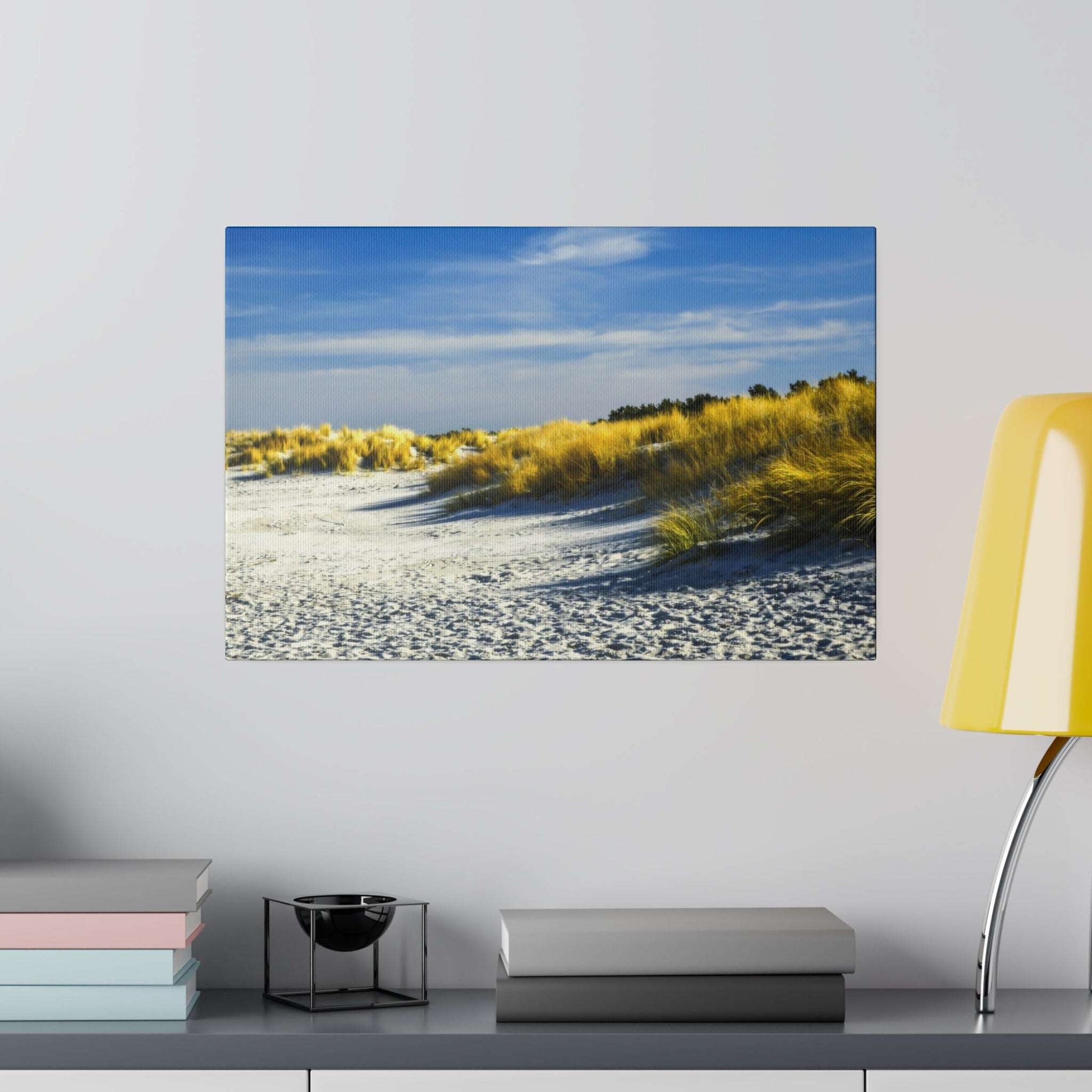 Framed beach scene showing white sand and yellow dune grasses under a blue sky.