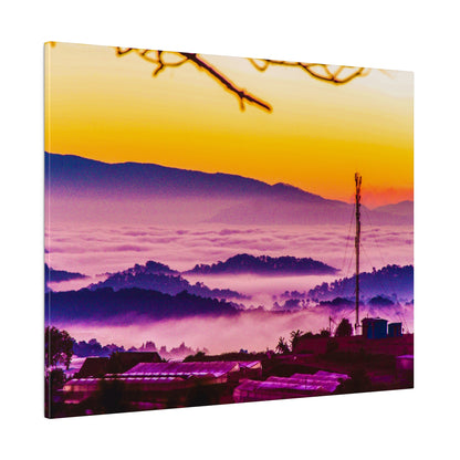 Colorful sunrise over fog-shrouded hills with a small town in the foreground and a tall antenna.
