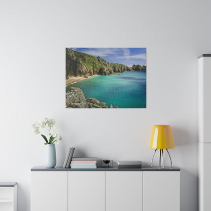 Canvas print of a rocky coastline with turquoise sea and sandy beach, hung on a white wall above a sideboard.