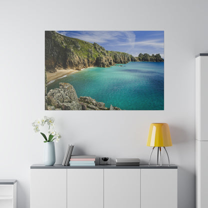 Framed coastal photo showing turquoise sea, sandy beach, and rocky cliffs above a white cabinet.