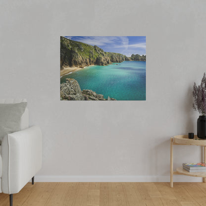 Photo print of a turquoise coastal cove with rocky cliffs and sandy beach, hung on a light gray living-room wall.