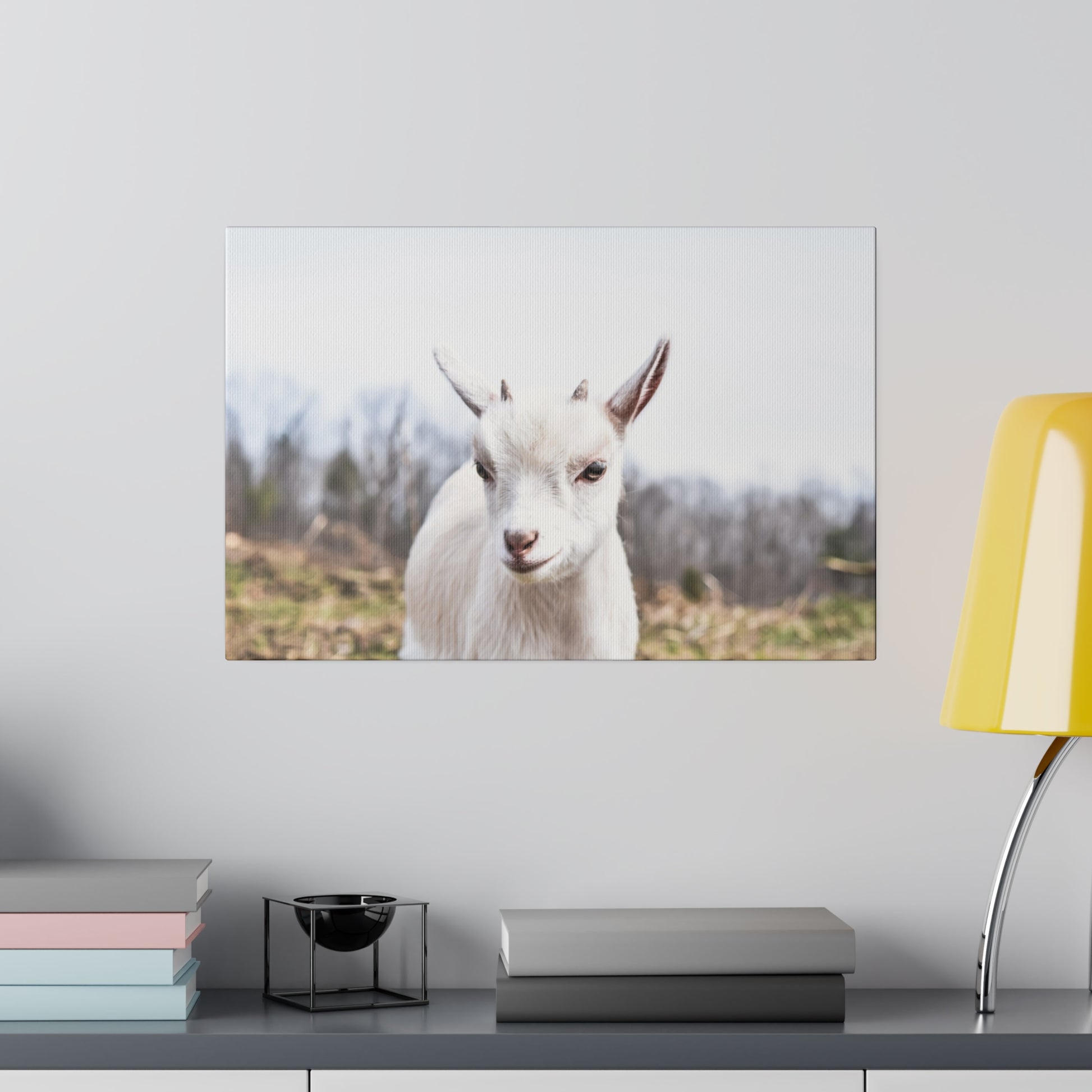 Wall-mounted canvas print showing a white goat with a brown nose against a rural landscape backdrop.