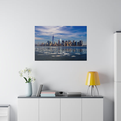 Framed daytime photo of a city skyline across a body of water, hung above a white cabinet.