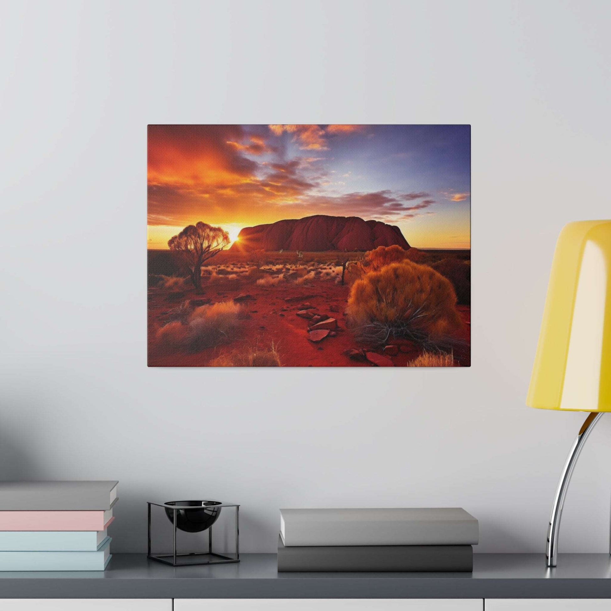 Canvas print of Uluru at sunset featuring red rock, orange sky, and sparse desert vegetation.