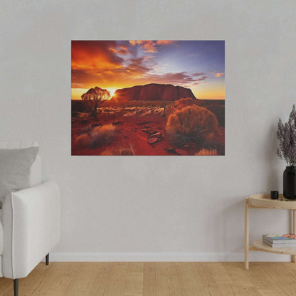 Canvas print of a desert scene featuring Uluru at sunset, orange sky, red soil and sparse shrubs.
