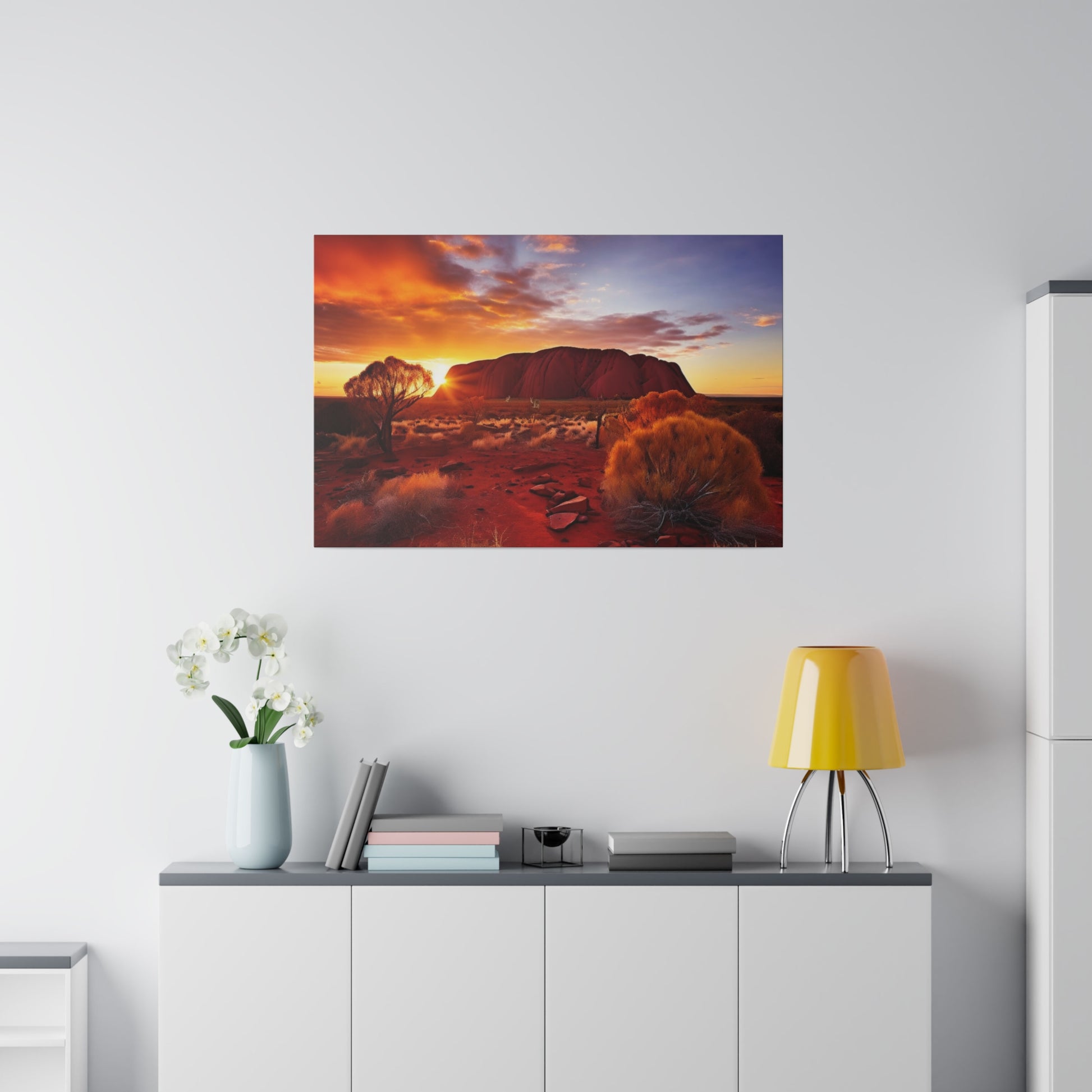 Framed landscape photo showing a desert at sunset with a large red rock formation and orange bushes.