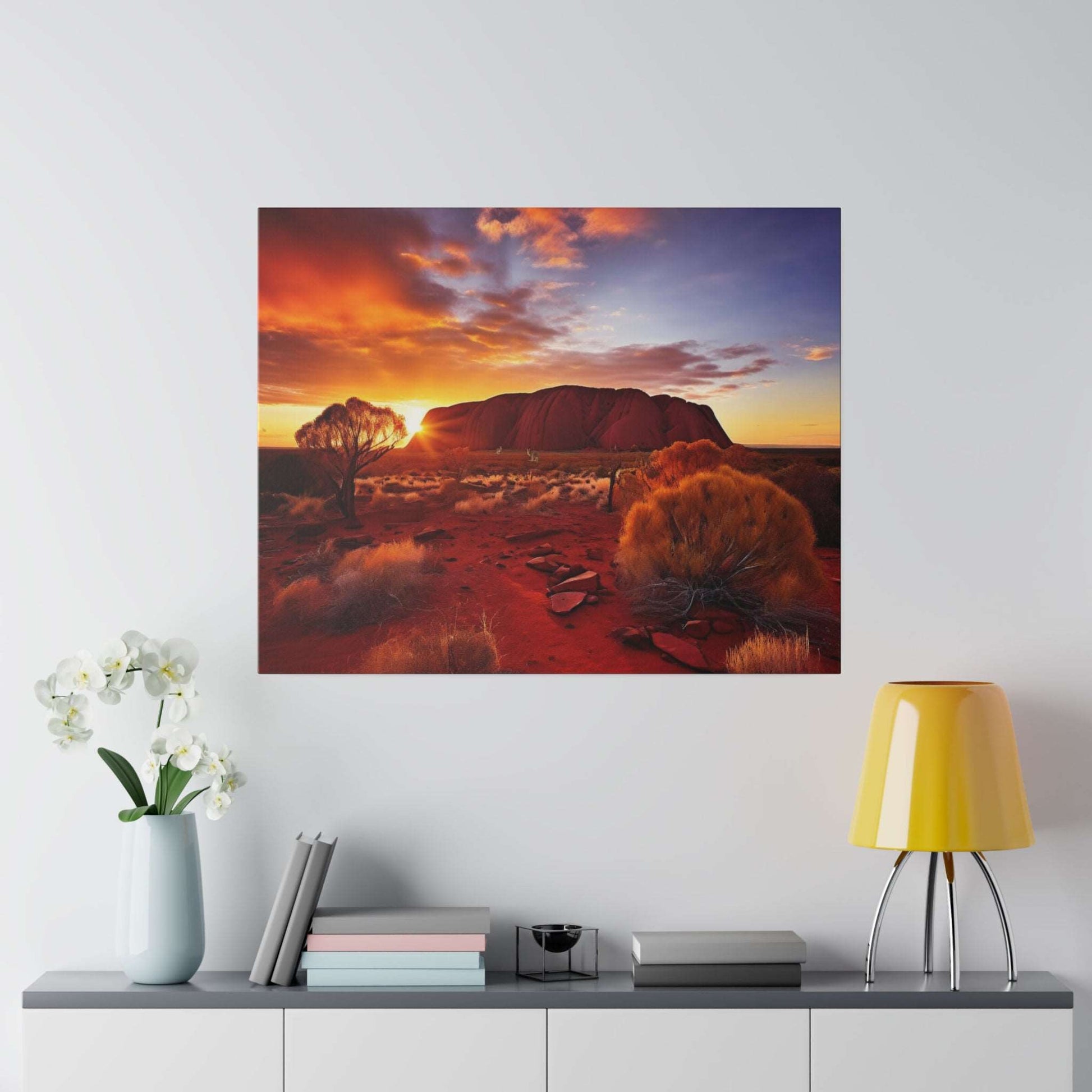 Desert landscape canvas print featuring Uluru at sunset, with red sand, orange and purple sky and sparse shrubs.