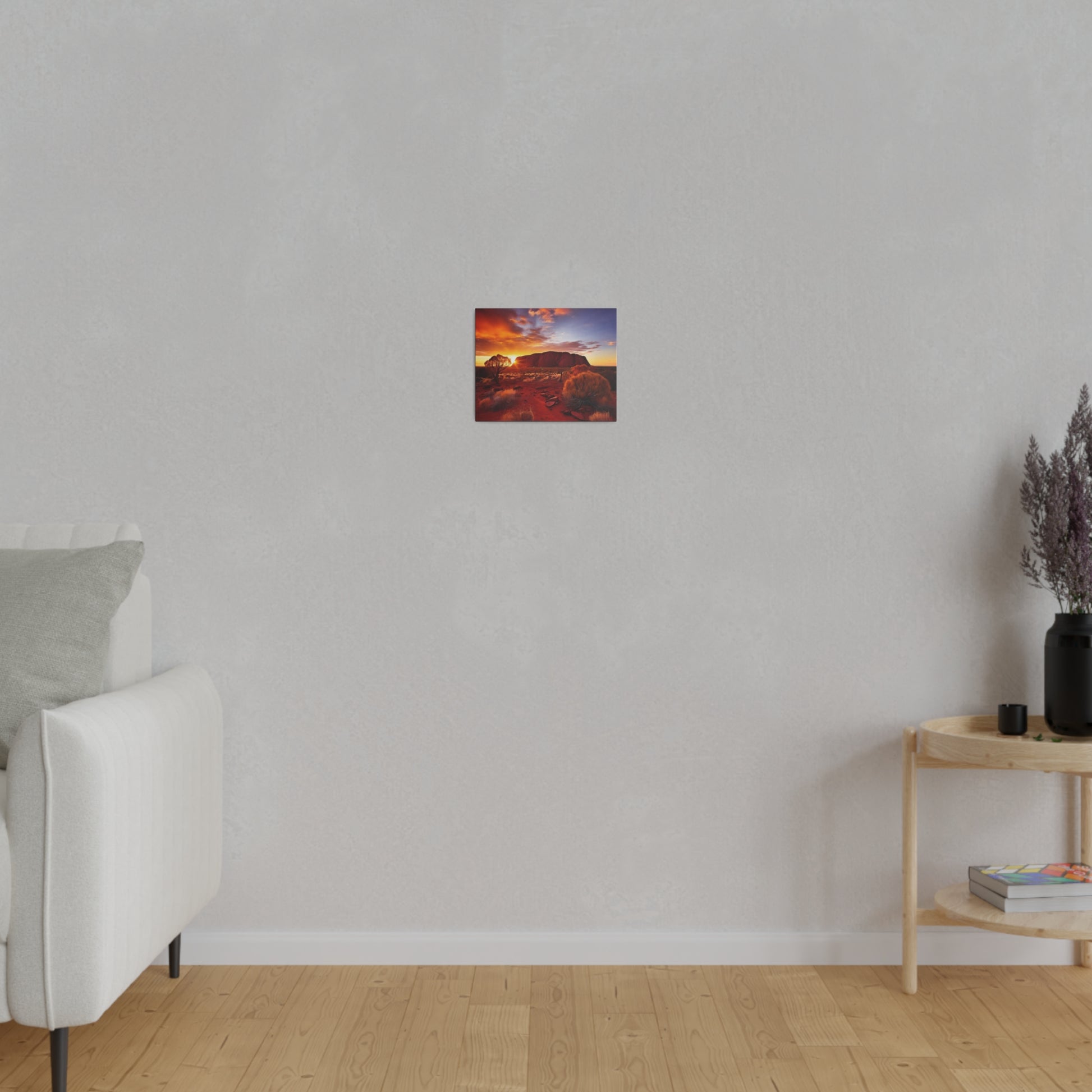 Small rectangular wall art depicting a desert landscape with an orange sunset, hung on a light gray wall above a wooden floor.