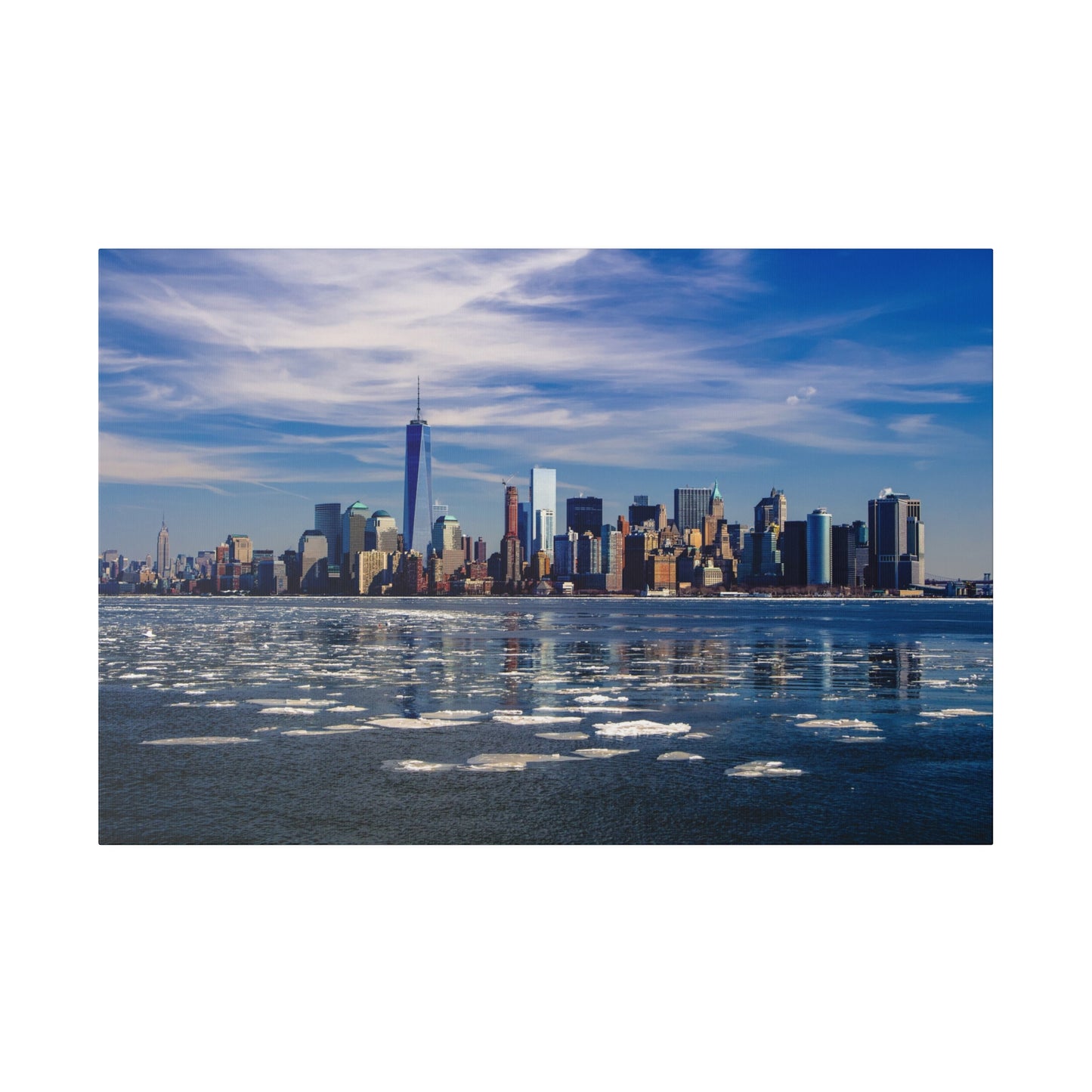 Downtown New York City skyline with a clear river view and patches of ice floating on the water on a sunny day.