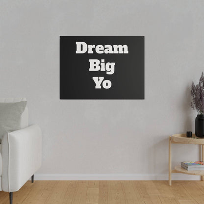 Black rectangular wall art with white bold text “Dream Big Yo” hanging on a light gray living room wall.