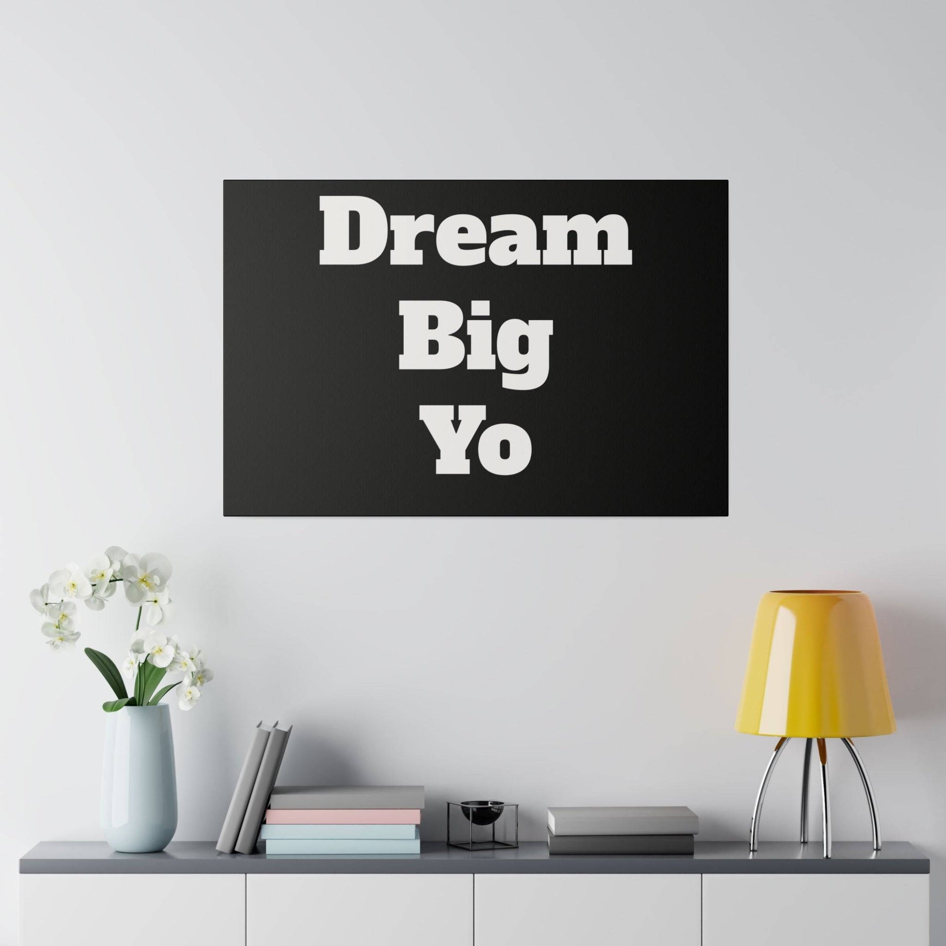 Black rectangular wall art with large white letters reading "Dream Big Yo" stacked in three lines.